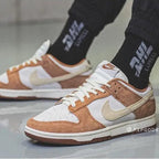 Brown and white sneakers with a visible Nike logo worn indoors on a gray floor.