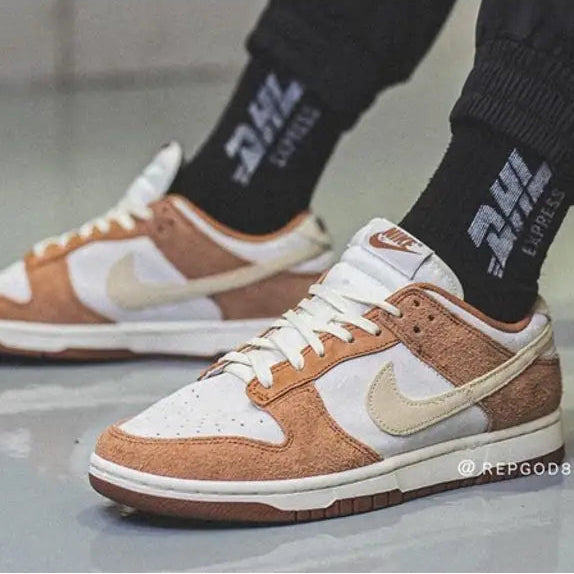 Brown and white sneakers with a visible Nike logo worn indoors on a gray floor.